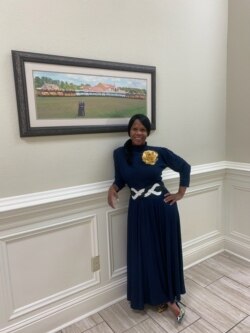 Courtney Tobias inside Life Tabernacle Church in Baton Rouge, posing in front of a photo of Pastor Tony Spell, his wife, and the church's bus fleet.