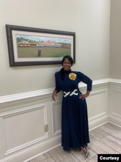 Courtney Tobias inside Life Tabernacle Church in Baton Rouge, posing in front of a photo of Pastor Tony Spell, his wife, and the church's bus fleet.