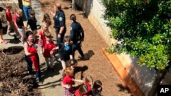 La police encadre les écoliers qui ont échappé à la fusillade à l’école presbytérienne de Nashville, aux États-Unis, le 27 mars 2023. 