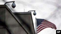 FILE - An American flag flutters beside CCTV cameras on top of the U.S. embassy in Berlin, Germany, Oct. 25, 2013.