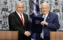 Israeli President Reuven Rivlin, right, shakes hands with Israeli Prime Minister Benjamin Netanyahu in Jerusalem, Sept. 25, 2109.