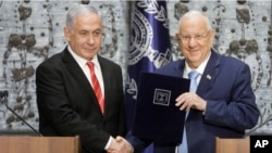 Israeli President Reuven Rivlin, right, shakes hands with Israeli Prime Minister Benjamin Netanyahu in Jerusalem, Sept. 25, 2109.