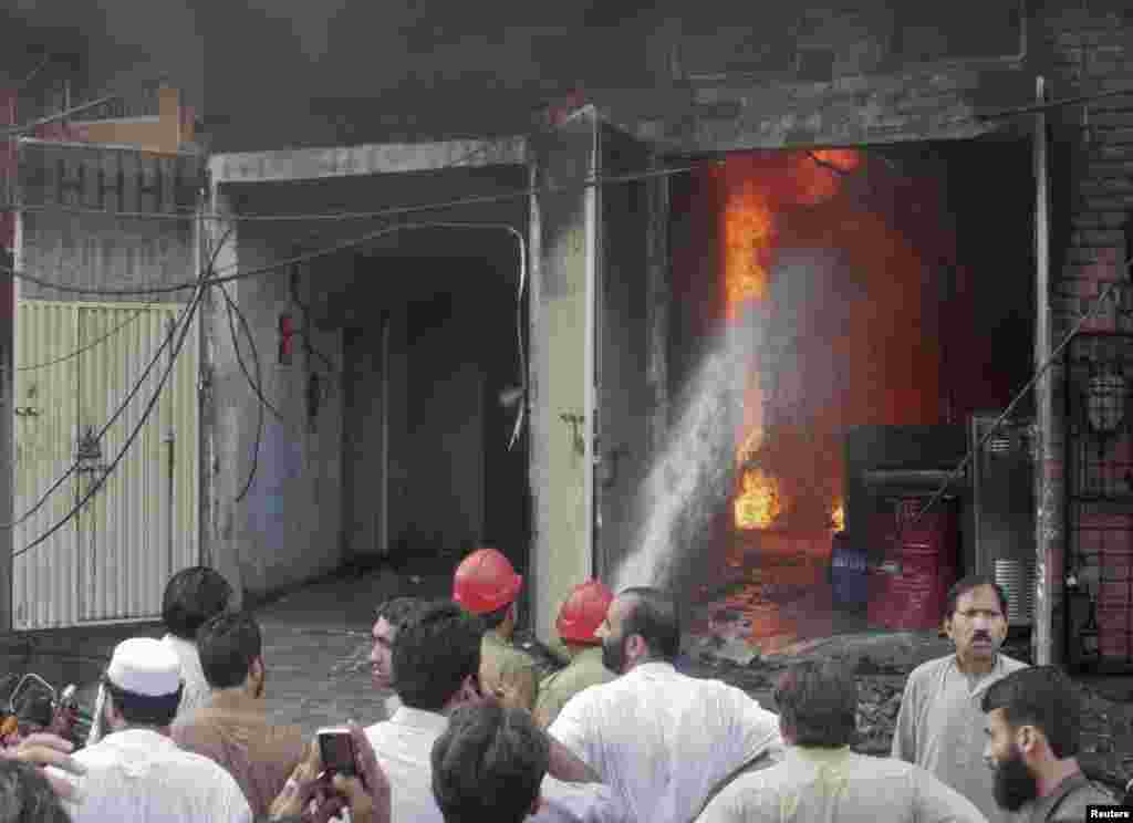 Residents gather while firefighters try to extinguish a fire at a shoe factory in Lahore, September 11, 2012. 