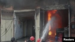 Residents gather while firefighters try to extinguish a fire at a shoe factory in Lahore, Sept. 11, 2012. 