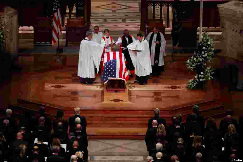 Members of the clergy bless the flag-draped casket of former President George H.W. Bush at the conclusion of his state funeral in the Washington National Cathedral in Washington, Dec. 5, 2018.
