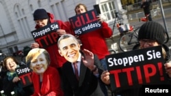 Demonstran anti perjanjian perdagangan Transatlantik memakai topeng Barack Obama dan Angela Merkel di Hannover, Jerman. (Foto: Dok)