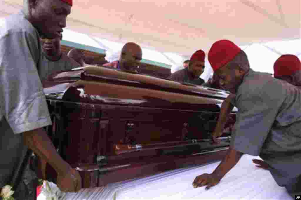 Masu shirye shiryen Bisne gawan Chinua Achebe ne ke kokarin dora akwatin dayake dauke da mamacin akan wani mumbari ,wanda yake shima wani tsari ne daga cikin bukukuwan janaizan. .