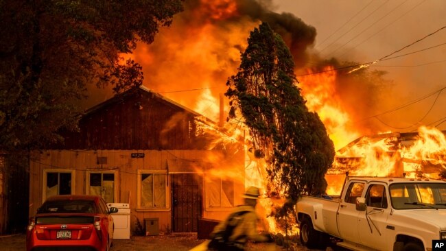 FILE - Fire consumes a home as the Sugar Fire, part of the Beckwourth Complex Fire, tears through Doyle, Calif., July 10, 2021.