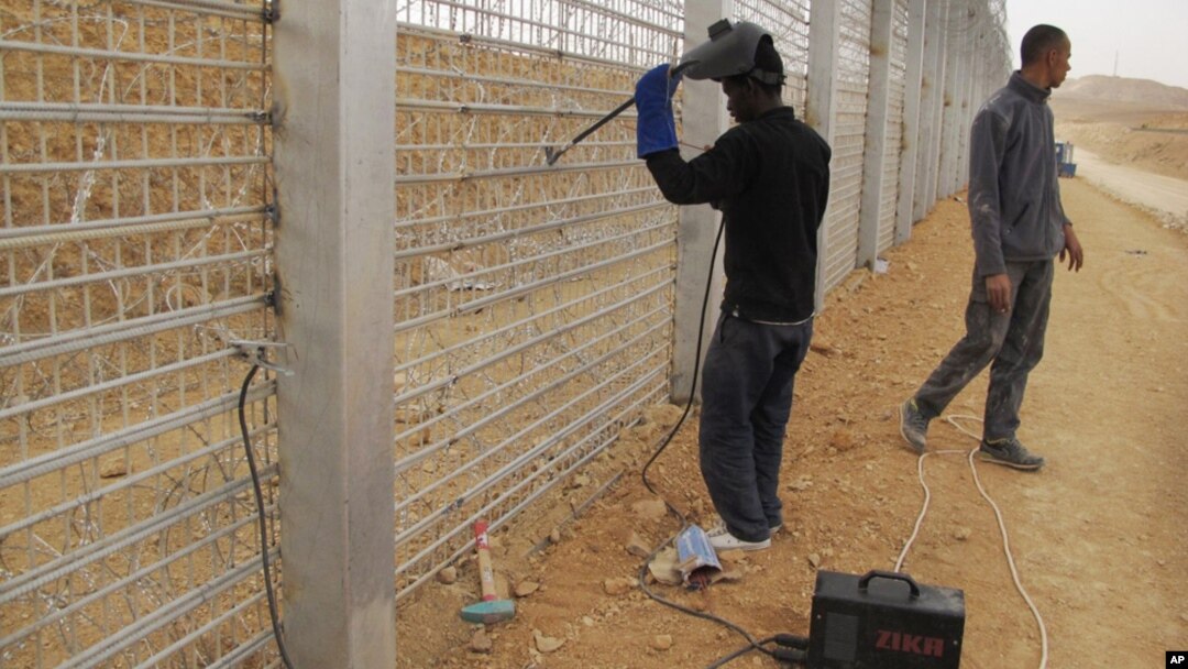 African migrants work at the site where Israel builds a barrier along the border with Egypt in southern Israel, February 15, 2012.