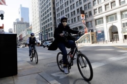 People wear mask as they ride bicycle in downtown Chicago, May 7, 2020.