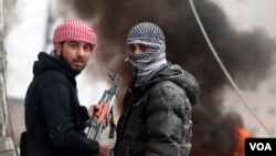 Free Syrian Army fighter look back as they stand in front of a burning barricade during heavy fighting in the Ain Tarma neighborhood of Damascus January 30, 2013.