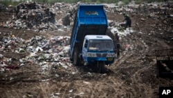 FILE - A garbage truck dumps trash at a site near a village in Zhanglidong, Henan province, China, Sept. 1, 2009.