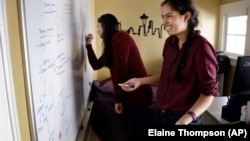 Aishwarya Mandyam, left, and her twin sister, Karishma Mandyam, write on an "idea board" for an upcoming startup competition at the University of Washington in Seattle. They're working on a mobile marketing startup.