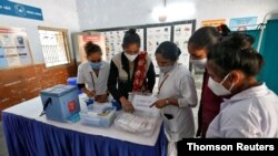 Health workers prepare a vaccination room inside a classroom of a school, which has been converted into a temporary COVID-19 vaccination centre in Ahmedabad, India, Jan 4, 2021.