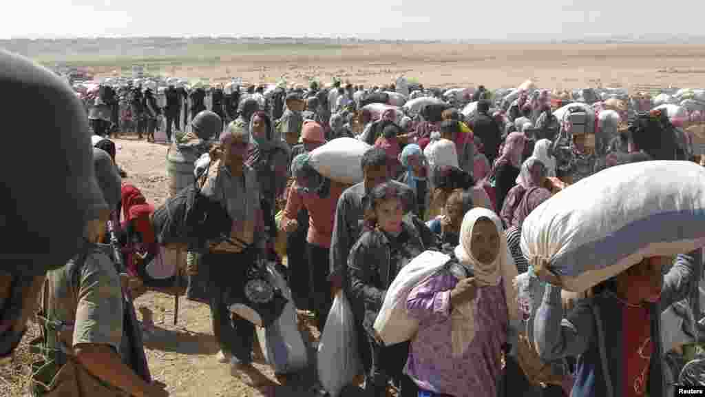 Turkish soldiers stand guard as Syrian Kurds cross the border fence into Turkey near the southeastern town of Suruc in Sanliurfa province, Sept. 19, 2014. 