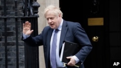 FILE - British Prime Minister Boris Johnson waves as he leaves 10 Downing Street in London, Feb. 12, 2020. Johnson has come under pressure to dismiss adviser Andrew Sabisky, who wrote offensive comments about race and intelligence in 2014 and 2016.