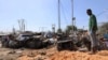 Seorang pria berdiri di lokasi ledakan bom mobil di sebuah pos pemeriksaan di Mogadishu, Somalia, 28 Desember 2019. (Foto: Reuters)