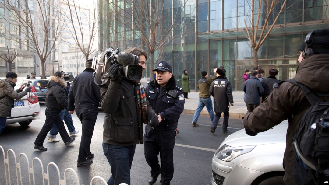 Polisi mencoba menghalangi jurnalis mewawancarai pengacara aktivis China Xu Zhiyong di luar pengadilan Beijing, Januari 2014.