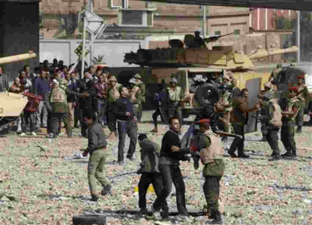 Miembros oficialistas resisten junto a los soldados, a las afueras de la plaza principal de El Cairo.