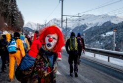 A man dressed as a clown is part of hundreds of climate protesters who are on a three-day protest march from Landquart to Davos, Switzerland, Jan. 20, 2020.