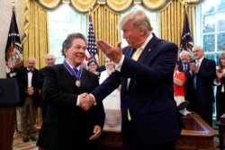 President Donald Trump shakes hands with economist Arthur Laffer after awarding him the Presidential Medal of Freedom, June 19, 2019, in the Oval Office of the White House in Washington.