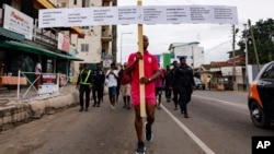 Texas Kadri Moro, the executive director of Arise for Justice International, protests with placards nailed on a cross on the street of Accra, Ghana, Sept. 12, 2024. 