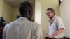 William John Endley, a South African national and an adviser to South Sudanese rebel leader Riek Machar, stands inside the dock in the High Court as his lawyer Gar Adel Gar looks on, in Juba, South Sudan, Feb. 13, 2018.