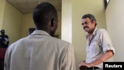 William John Endley, a South African national and an adviser to South Sudanese rebel leader Riek Machar, stands inside the dock in the High Court as his lawyer Gar Adel Gar looks on, in Juba, South Sudan, Feb. 13, 2018.