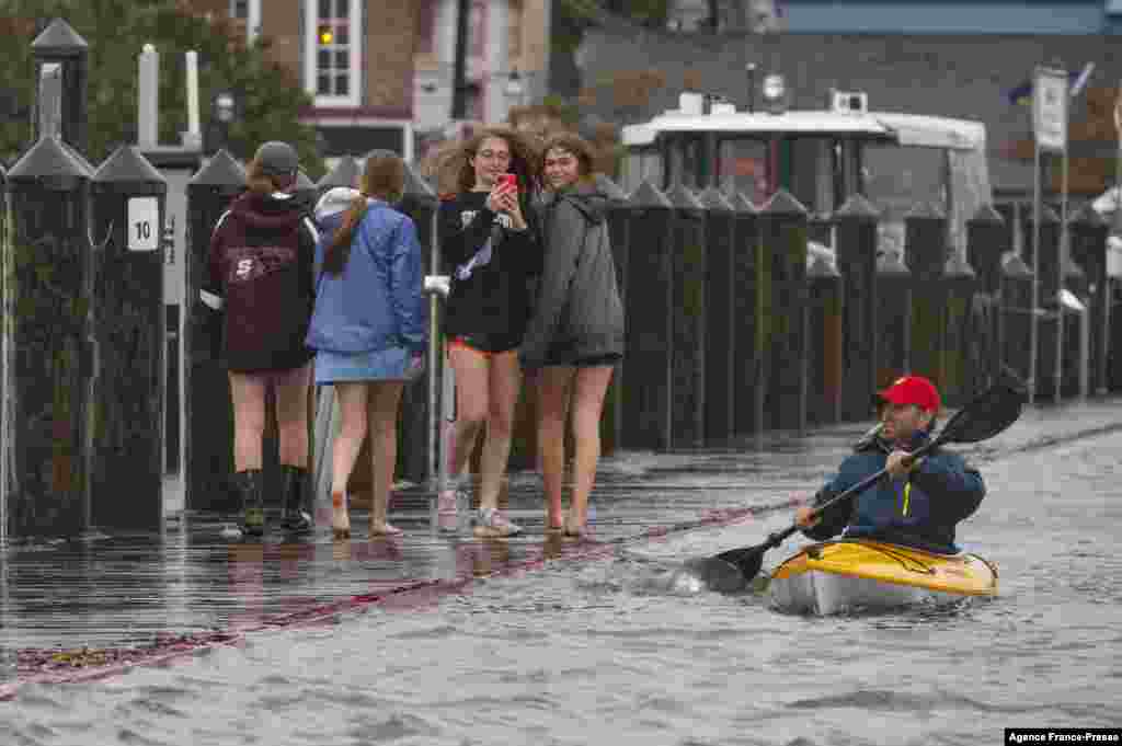 A group of people walk on the sea wall as a man kayaks through the flooded parking lot in downtown Annapolis, Md., on Oct. 29, 2021.