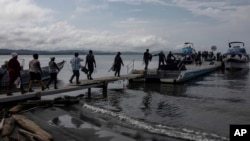 ARCHIVO - Migrantes abordan barcos hacia el Tapón del Darién, en Necoclí, Colombia, 7 de octubre de 2023. 