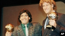 ARCHIVO - La estrella Diego Maradona, izquierda, y el portero de Alemania Occidental Harald Schumacher sostienen sus trofeos de la Copa Mundial de Fútbol, durante la ceremonia del Premio de la Bota de Oro de Fútbol celebrada en París, Francia, el 13 de noviembre de 1986. 
