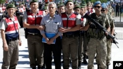 Paramilitary police and members of the special forces escort former Air Force commander Akin Ozturk and other suspects of last year's failed coup, outside the courthouse at the start of a trial, in Ankara, Turkey, Tuesday, Aug. 1, 2017.