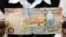 ARCHIVES - Un homme montre un billet de 50 000 Kwacha, la monnaie zambienne, à Lusaka le 23 janvier 2012.
