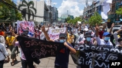 Protesters hold banners as they make the three-finger salute during a demonstration against the military coup in Yangon, Myanmar, May 12, 2021.