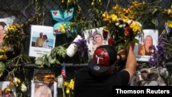 A man places flowers on a makeshift memorial for the victims of the Surfside's Champlain Towers South condominium collapse in Miami, Florida, July 9, 2021.