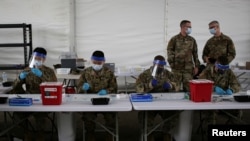 FILE - U.S. Army soldiers prepare COVID-19 vaccine shots to be administered at a vaccination site in Miami, Florida, March 10, 2021. U.S. military members themselves will soon be required to get inoculated against COVID-19. 