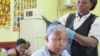 Rita Dantaa, who owns a hair salon in downtown Johannesburg, applies relaxer to her client's hair, May 16, 2014 (Gillian Parker for VOA).