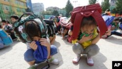 Elementary school students, with schoolbags on their heads, take shelter on the ground during an earthquake drill at Songjung Elementary School in Seoul, South Korea, Sept. 23, 2016. 