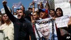  supporter of Caracas Mayor Antonio Ledezma holds a poster of him with chains during a protest demanding his release in Caracas, Venezuela, Friday, Feb. 20, 2015.