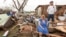 FILE - Raella Faulkner, at left, and Bobby McElroy survey what's left of their home, April 28, 2014, after a tornado struck the town of Vilonia, Arkansas. 