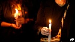 People hold candles during a protest against the murder of journalist Lourdes Maldonado and freelance photojournalist Margarito Martinez, which occurred in Tijuana within the span of a week, in Mexico City, Tuesday, Jan. 25, 2022.