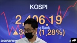 A currency trader walks by the screen showing the Korea Composite Stock Price Index (KOSPI) at the foreign exchange dealing room in Seoul, South Korea, Sept. 10, 2020.