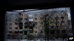 ARCHIVO - Un edificio residencial que fue destruido por las fuerzas rusas se ve a través de la ventana rota, en la ciudad fronteriza de Vuhledar, Ucrania, el 25 de febrero de 2023. 