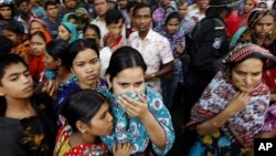 People look at a burnt garment factory outside Dhaka, Bangladesh, November 25, 2012.