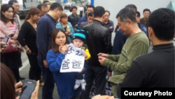 小孩拿著“還我爸爸”的標語（圖片來自新世紀新聞網/網民提供）