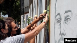 People put white roses on portraits of victims of last year's Beirut port blast as Lebanon marks one year anniversary of the explosion, in Beirut, Lebanon, Aug. 3, 2021.