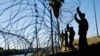 FILE - Members of the U.S. military install multiple tiers of concertina wire along the banks of the Rio Grande near the Juarez-Lincoln Bridge at the U.S.-Mexico border, in Laredo, Texas, Nov. 16, 2018.