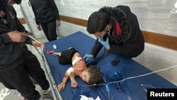 A wounded Palestinian girl is assisted as she lies on a bed at Kamal Adwan Hospital, during the ongoing Israeli military operation, amid the Israel-Hamas conflict, in Beit Lahiya, in the northern Gaza Strip, Dec. 17, 2024. 