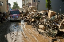 A fire department vehicle drives through a street lined with debris after extreme weather in Bad Neuenahr-Ahrweiler, Germany, July 18, 2021.