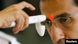 FILE - A health worker uses an infrared thermometer to check the temperature of a student for the Influenza A (H1N1) awareness at a university in Manila.